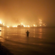 A man watches a wildfire approach the beach in Evia, Greece, in August 2021.